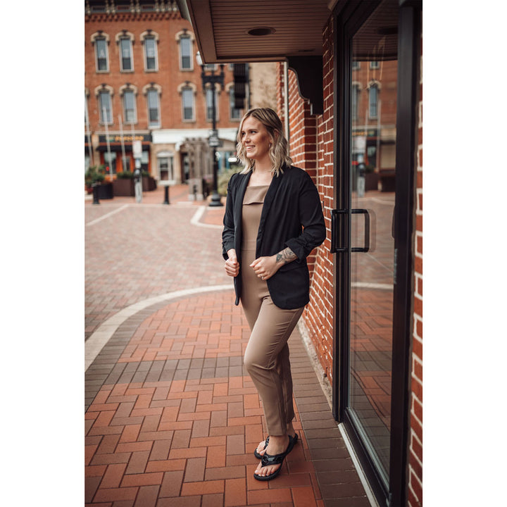 PowerStep Orthotic Arch Supporting fashion sandals for Women, woman standing in city surrounded by red brick buildings and brick ground while wearing black fashion sandals with arch support