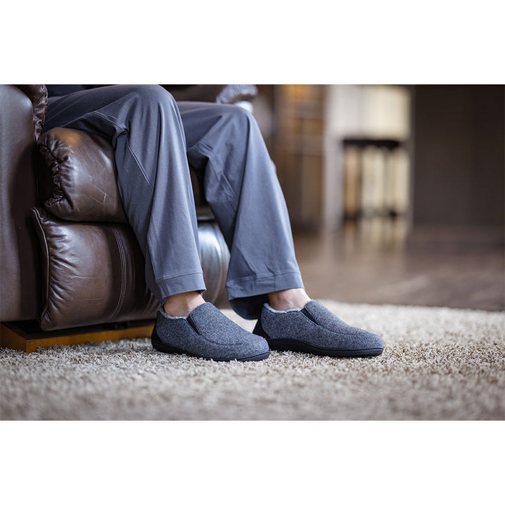 PowerStep Orthotic Arch Supporting slippers for Men, man sitting on couch while wearing orthotic arch supporting slippers, charcoal and light gray 
